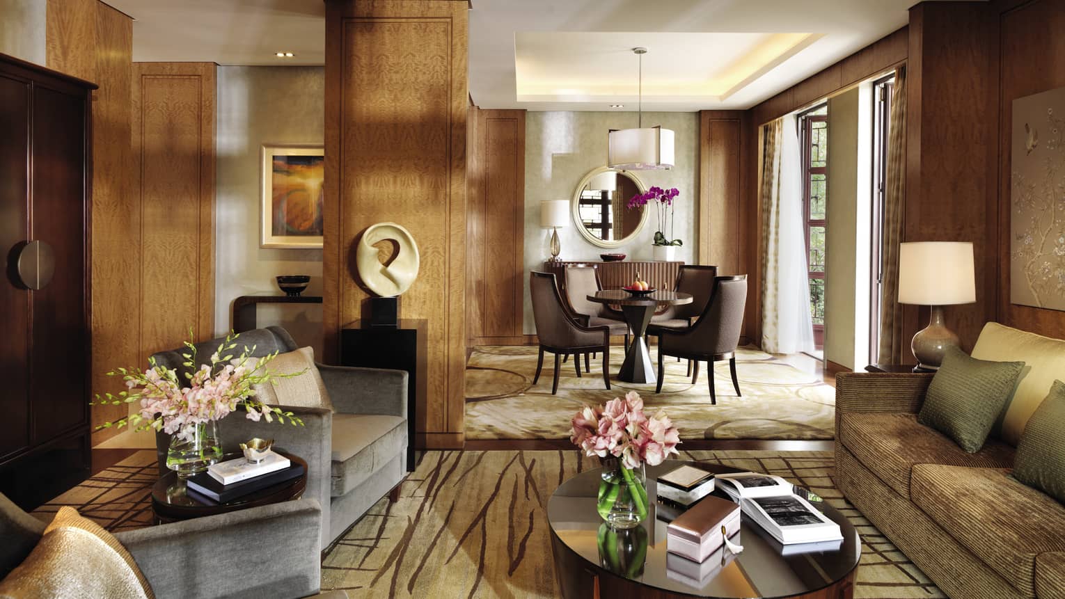 Lagoon Suite living room with modern sofas, chairs, table, art, by sunny dining room