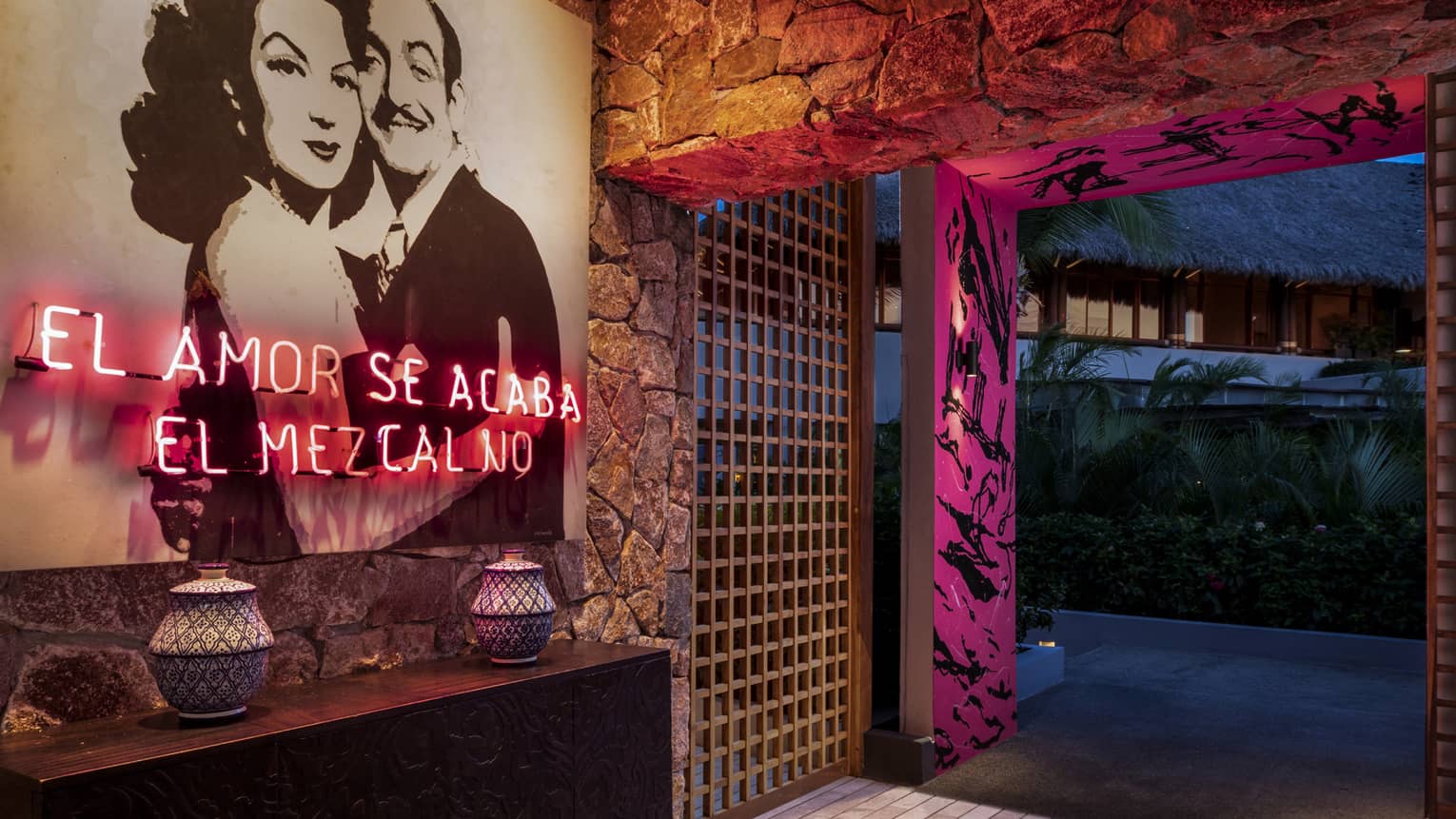 The interior entrance of a bar with a photo of a man and woman hugging and pink lighting.