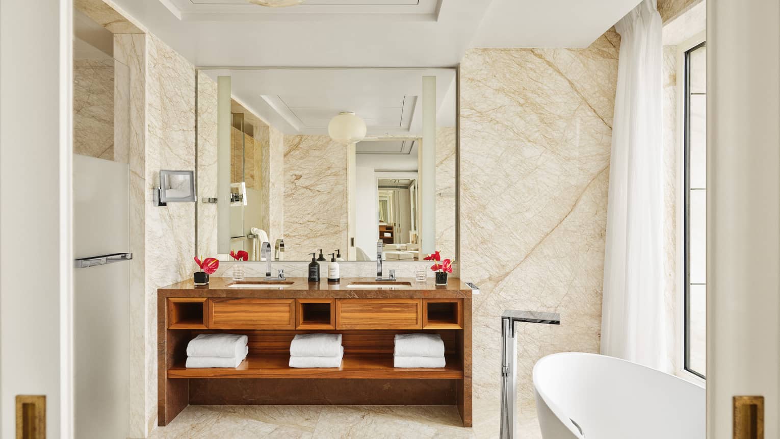 Luxury marble bathroom of hotel suite with standalone tub by window