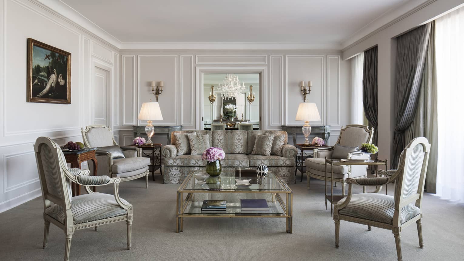 Sophisticated living room with classic furniture, patterned sofa, armchairs, glass coffee table and ornate wall paneling.