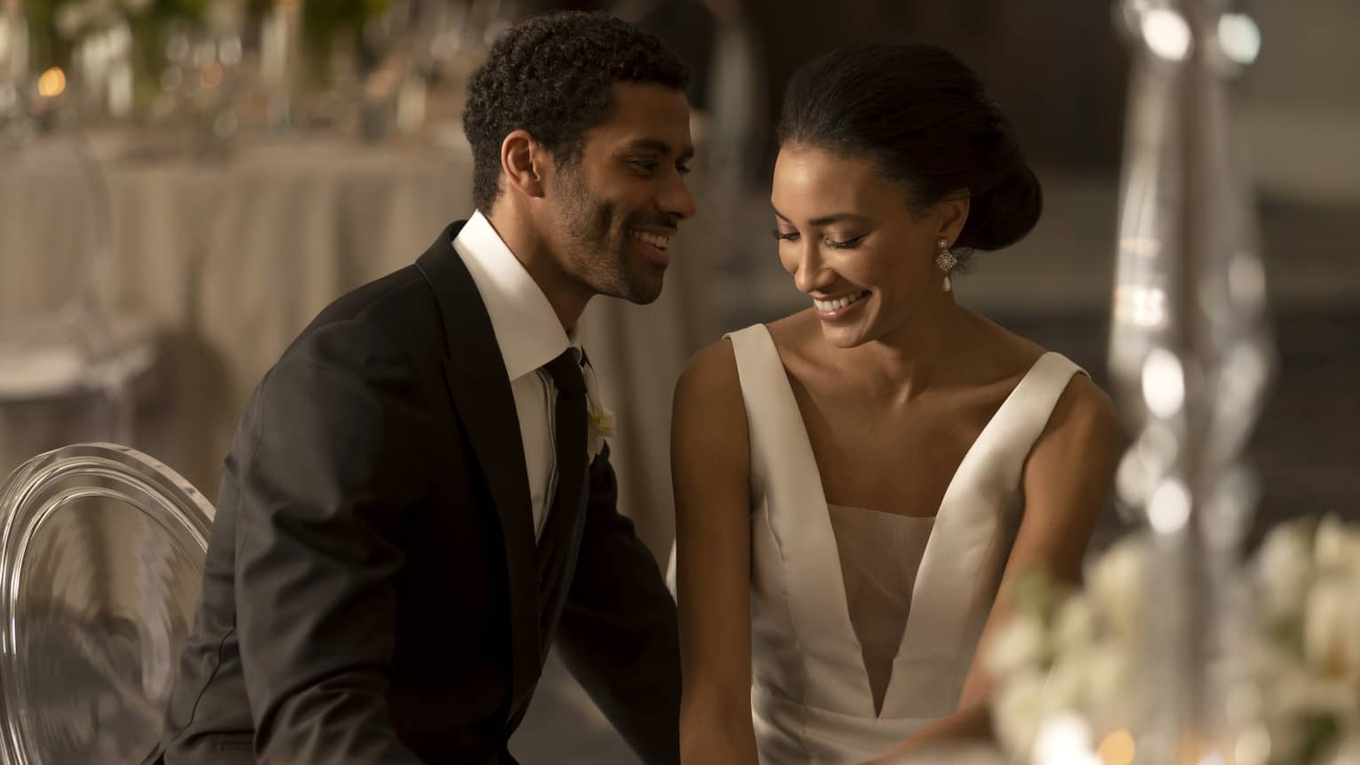 A bride and groom sitting at a table with candles.
