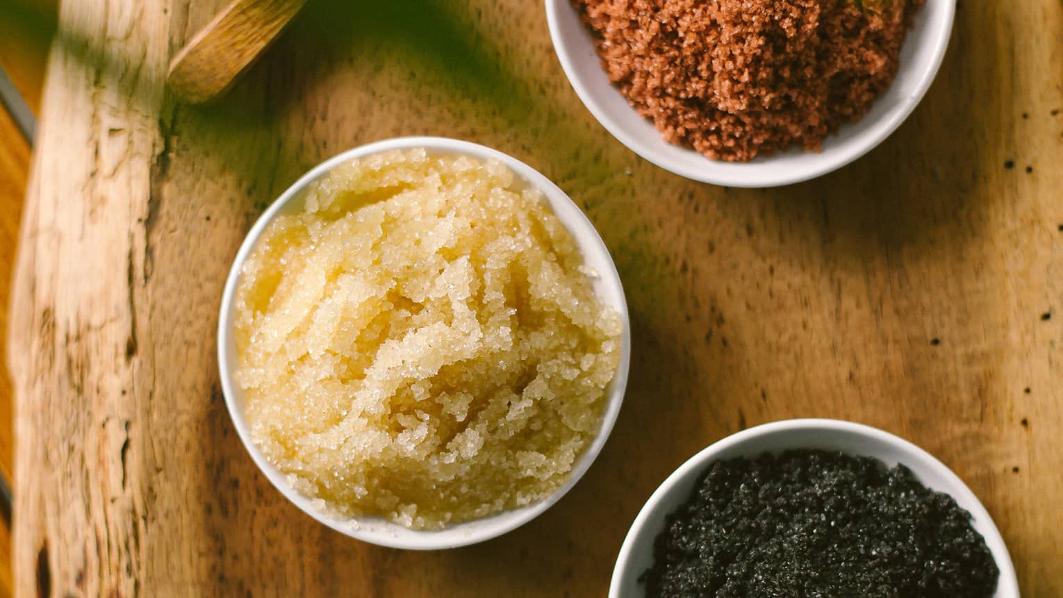 Aerial view of three dishes with salt scrubs on rustic wood platter