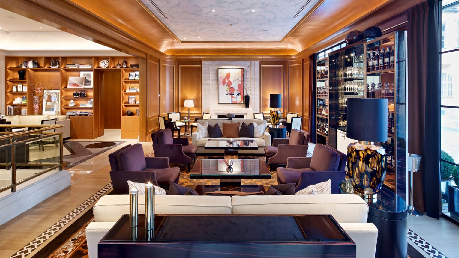 The Gallery bar and lounge with clusters of purple sofas, white armchairs, wall with wine and liquor bottles