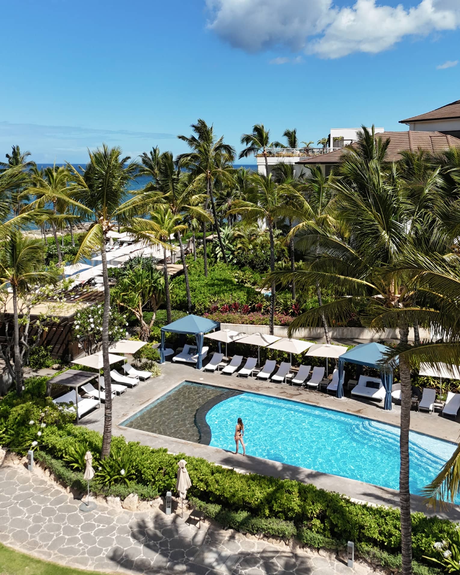 Family pool at luxury Hawaiian resort, lined with beach chairs and cabanas
