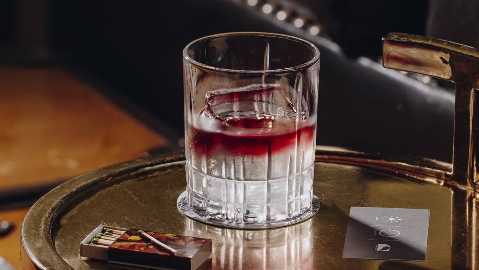 A red and clear cocktail on a tray.