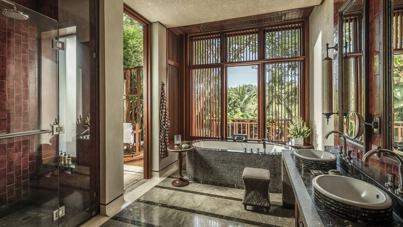 A sunlit bathroom with a tub and two sinks 