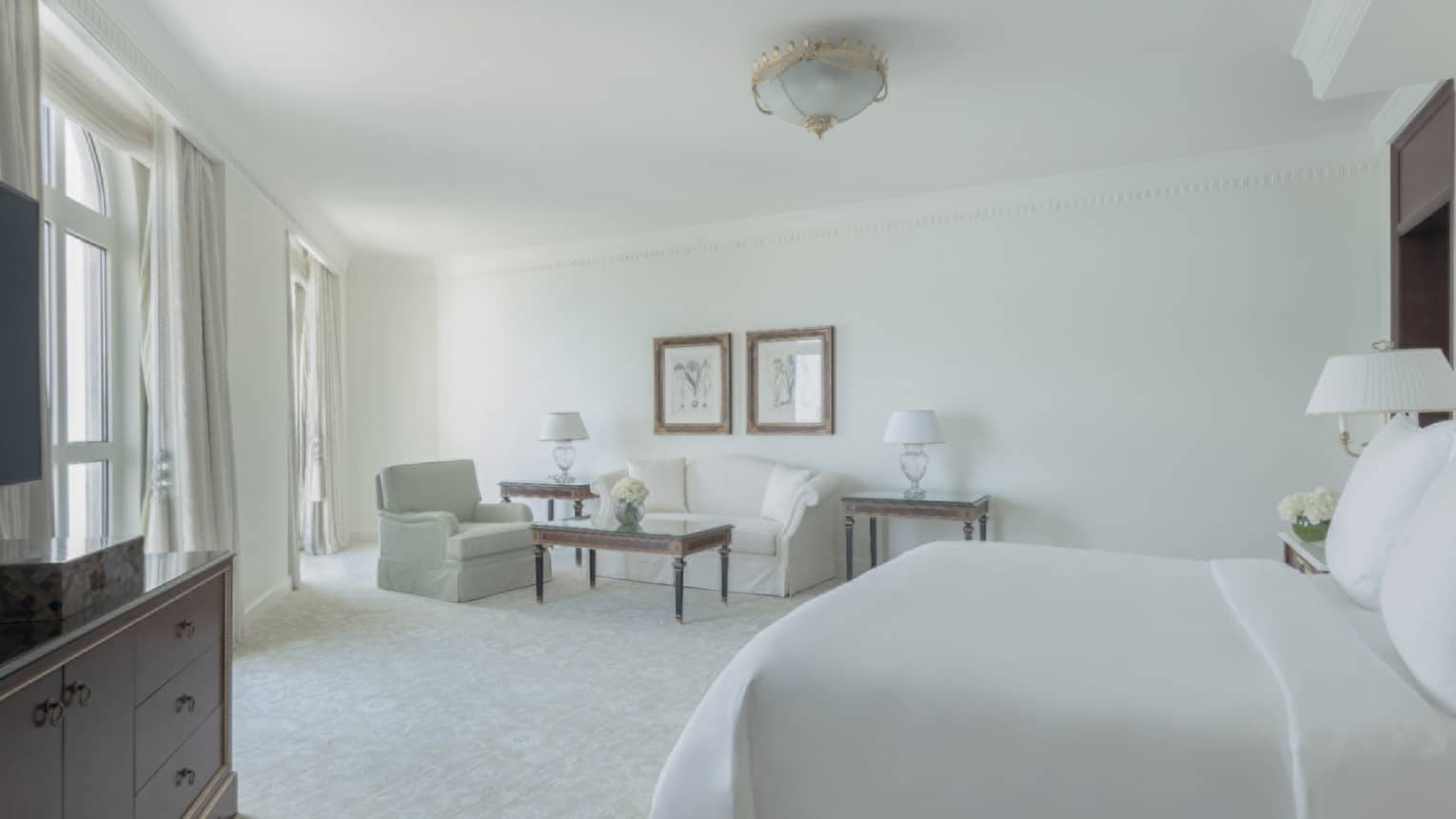 Bedroom with white walls, carpet, bedding, sofa and armchair