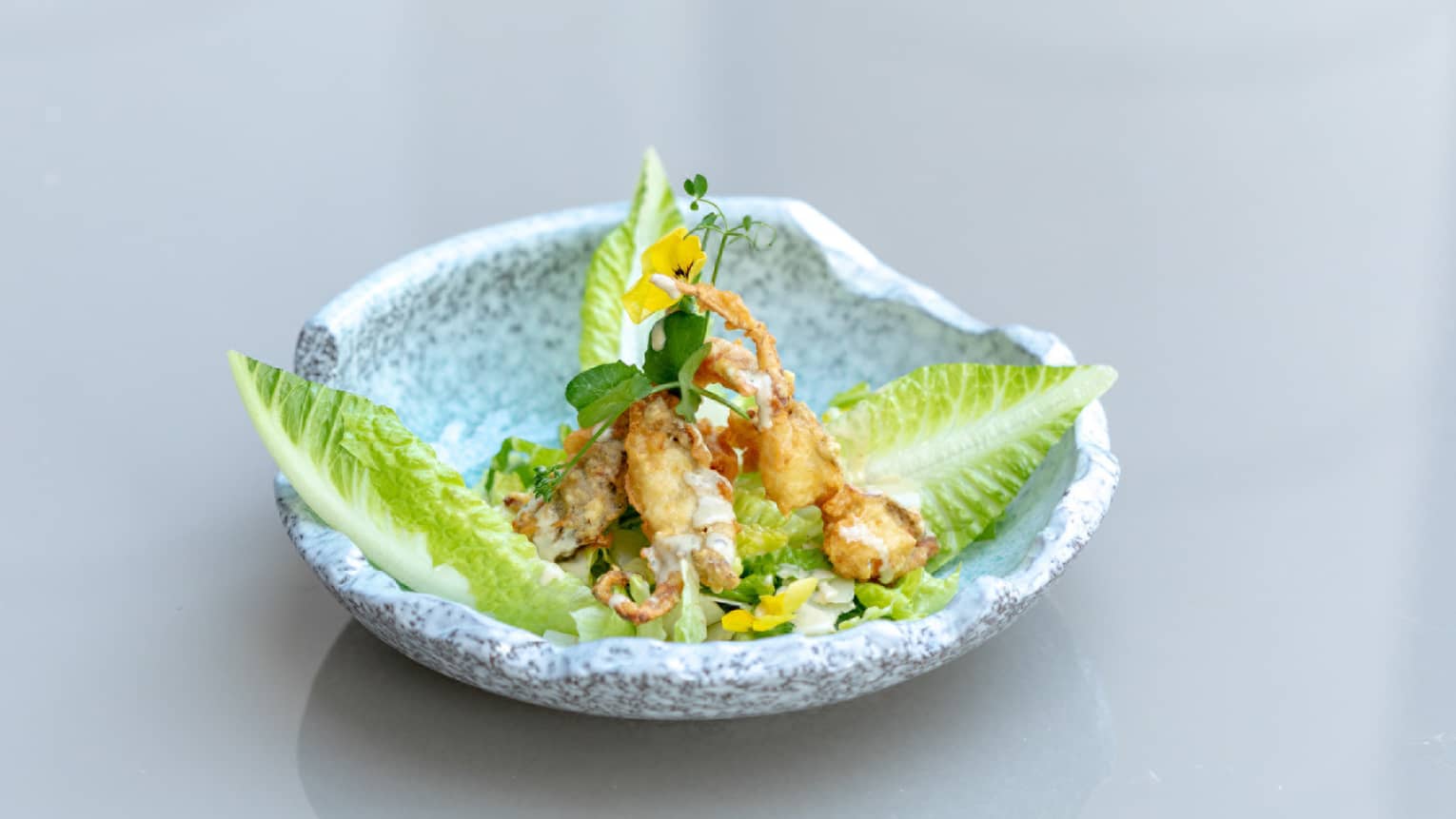 Ceasar Salad with Soft Shell Crab plated in an organic-shaped light-grey stoneware bowl