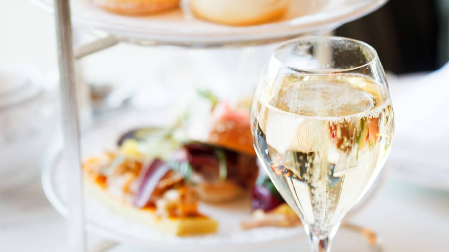Trays of pastries and small food next to a glass of wine.