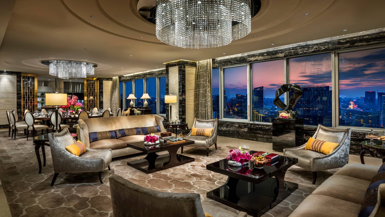 Imperial Suite luxurious living room with sofas, armchairs under large crystal chandeliers, floor-to-ceiling windows, sunset views
