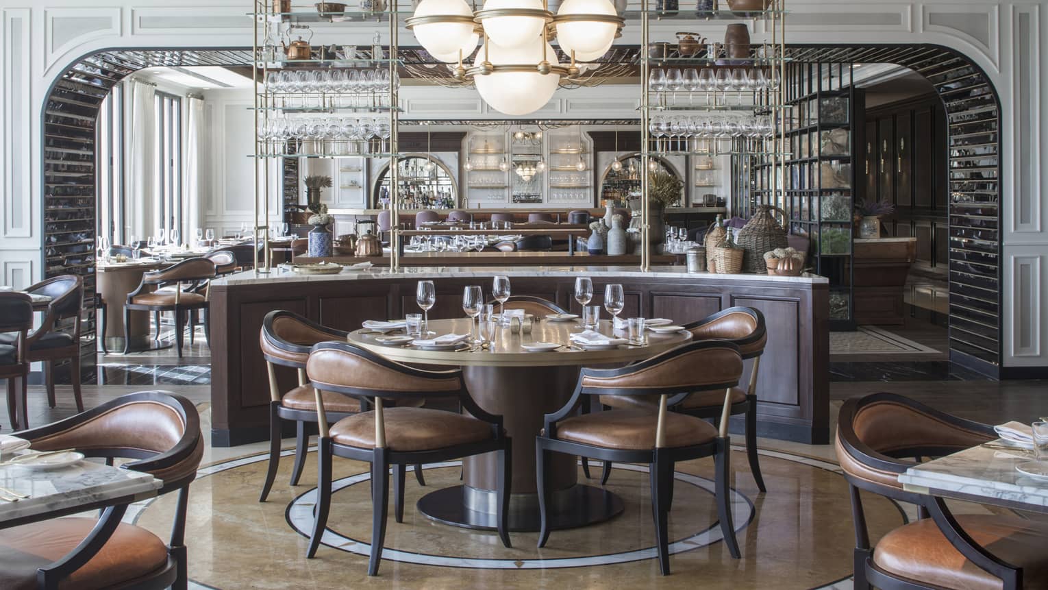 An art-deco restaurant features tables with low-back brown-leather chairs and a counter with copper kettles and wicker jugs.