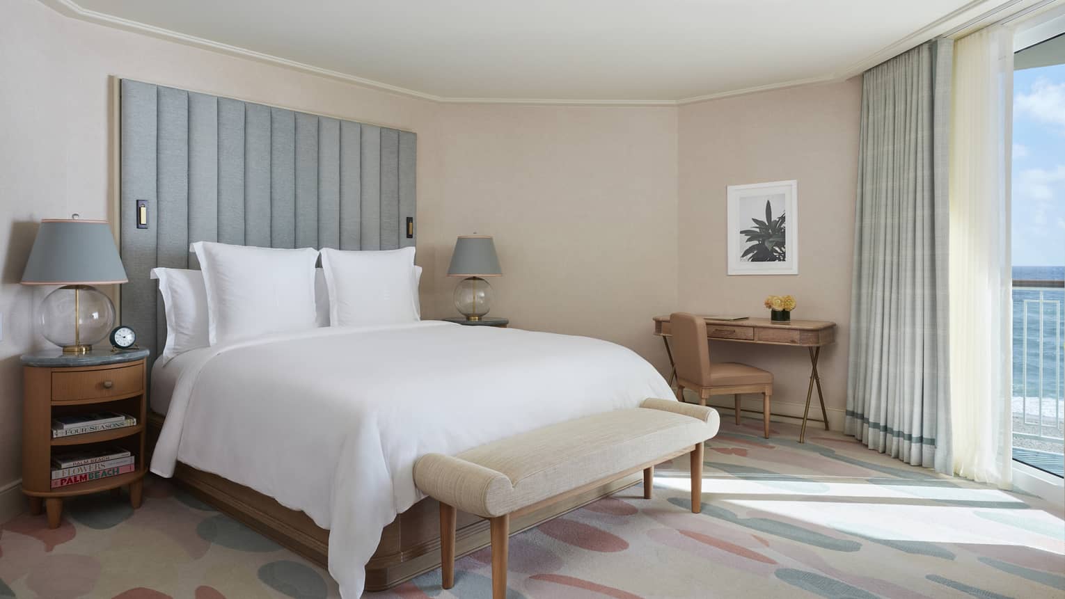 Bedroom of a hotel suite, with floor-to-ceiling views of the ocean