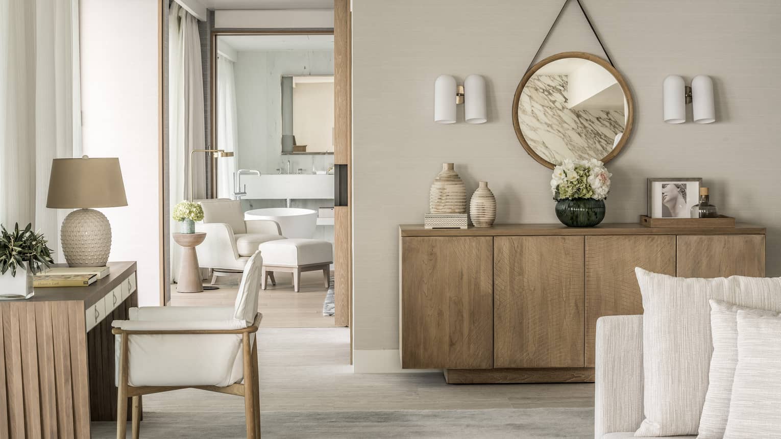 Arion Sea View Suite with white sofa, blonde wood sideboard and matching desk, doorway to bathroom