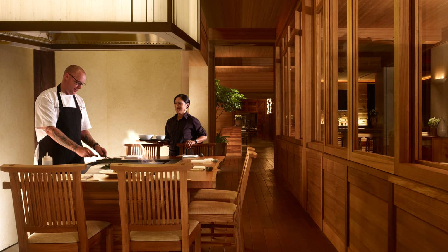 Chefs work at grill as flames leap out around him at small bar in NOBU restaurant