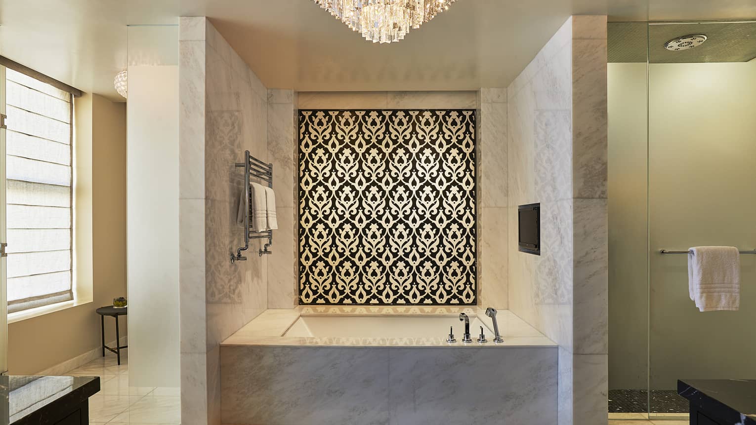 Large marble bathroom with deep soaking tub, separate glass-enclosed shower and chandelier