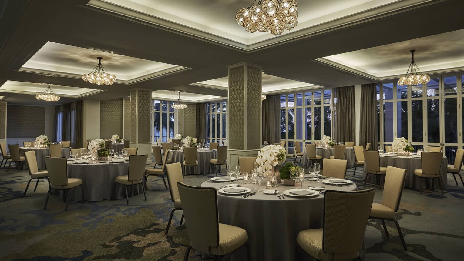 Round tables, chairs in dimly-lit Malolo Room banquet space 