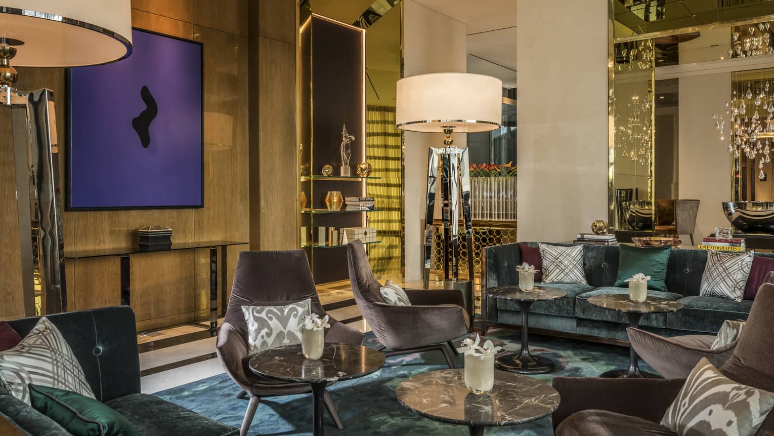 Penrose Lounge seating area with mid-century style velvet armchairs, accent pillows, tall lamps