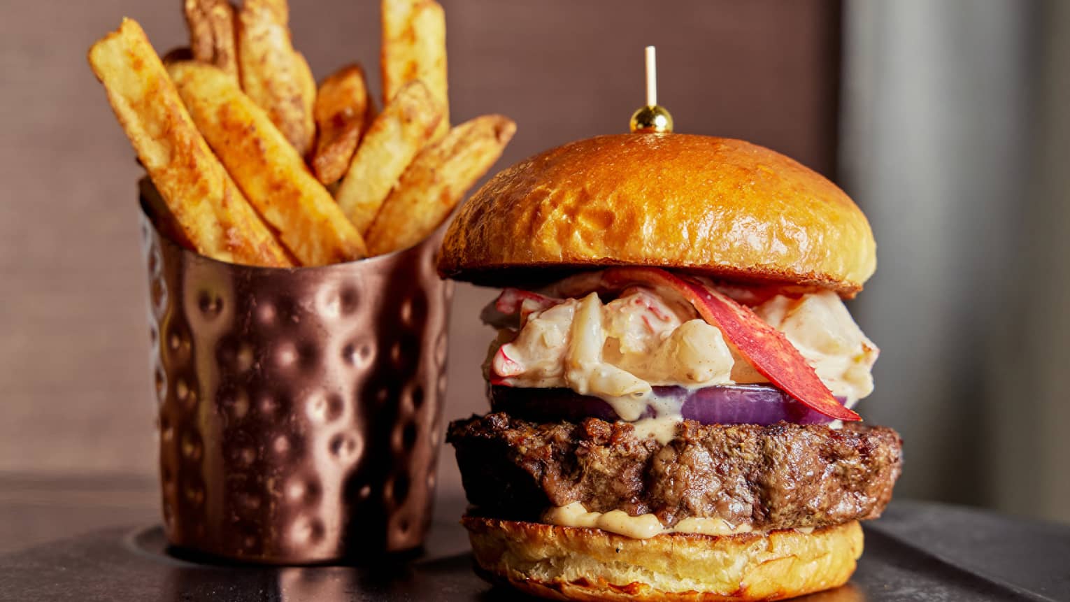 A burger and fries on a black plate.