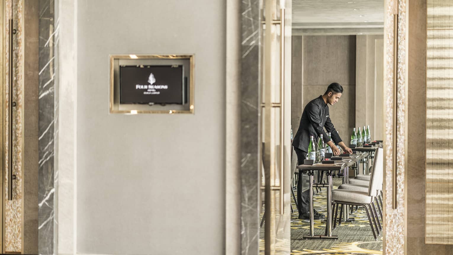 View through door with marble moulding as hotel staff sets meeting tables