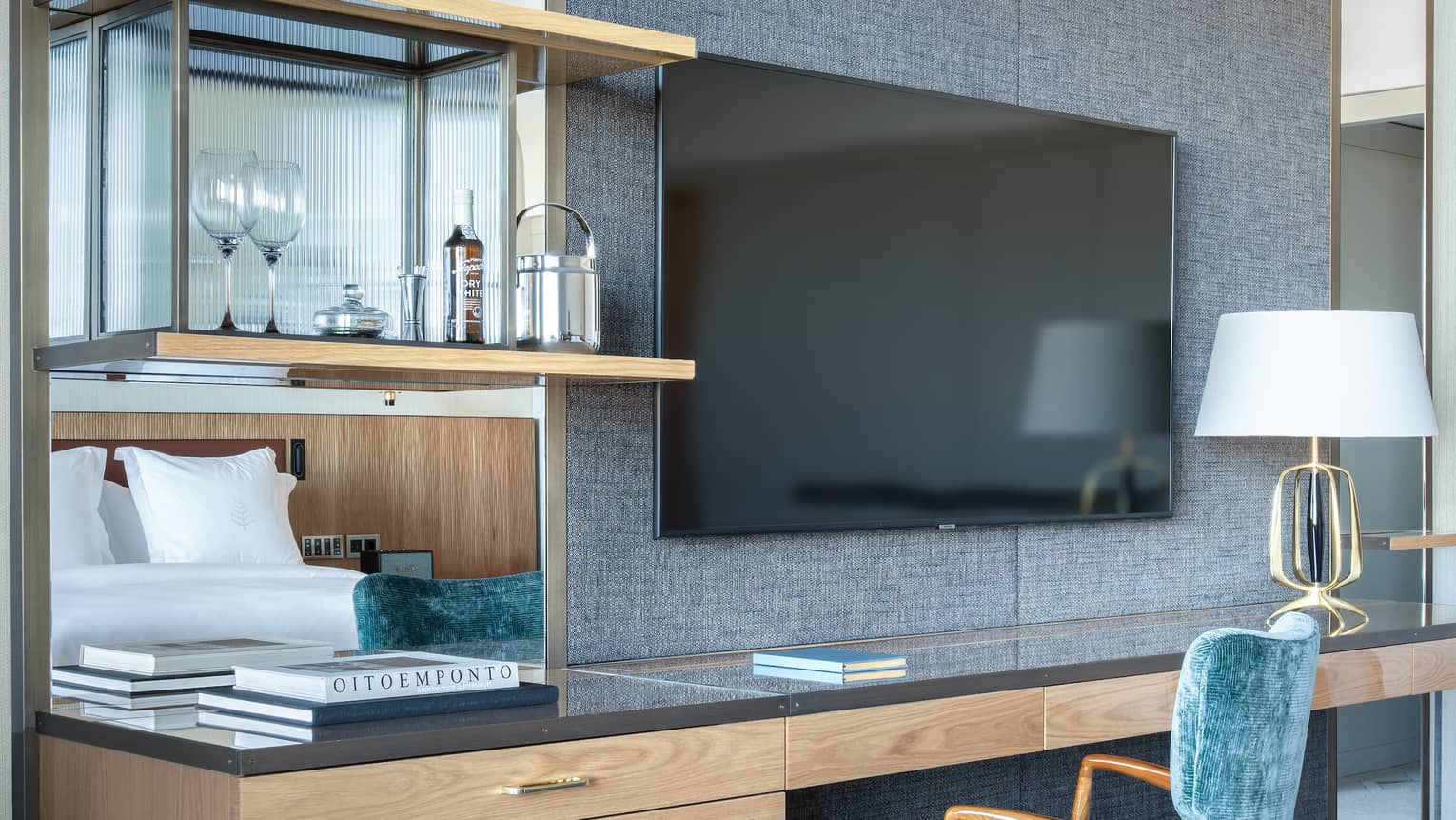 Close-up of guest room contemporary desk with blue chair, TV on fabric-backed wall