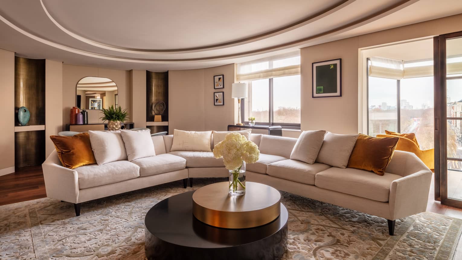 Hyde Park Suite living room with beige sectional, round coffee table with white flowers in vase