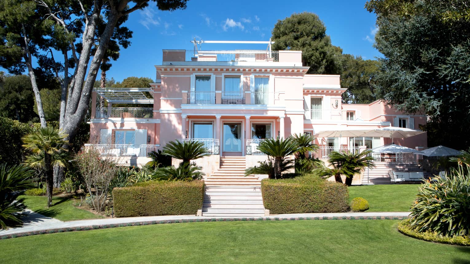 Manicured gardens, steps up to large three-storey pink Villa Rose-Pierre