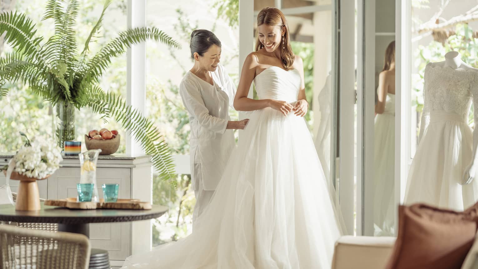 Wedding tailor helps bride in her wedding dress