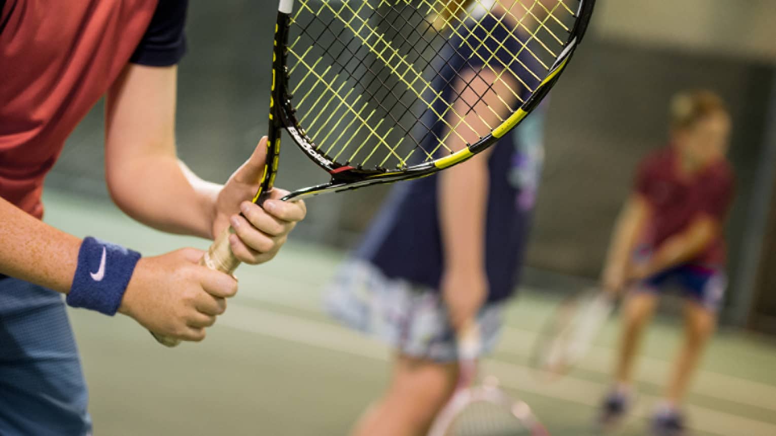 Close-up of hands holding yellow-and-black tennis racket