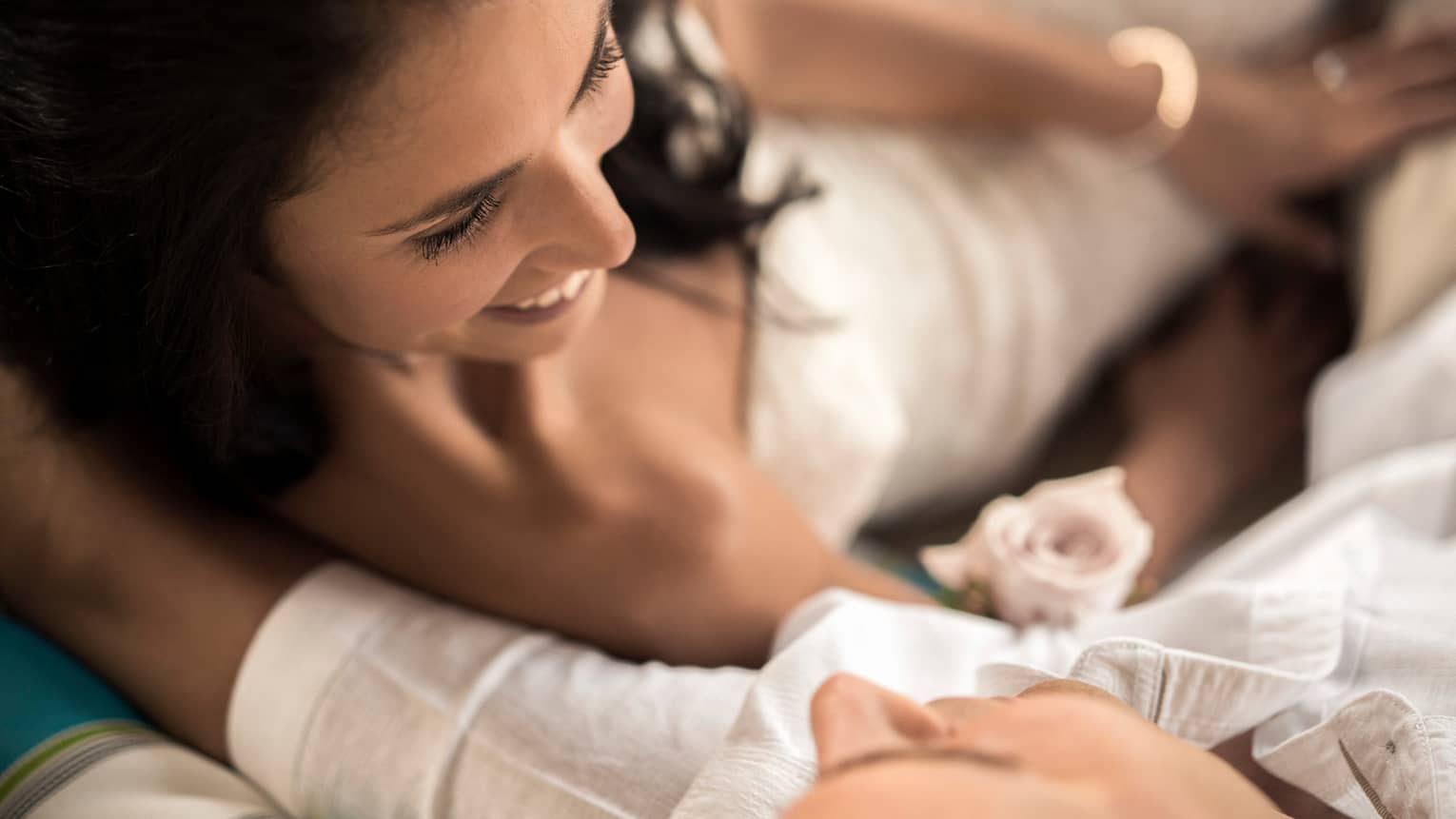 Woman in white dress and man with white shirt smiling at each other closely