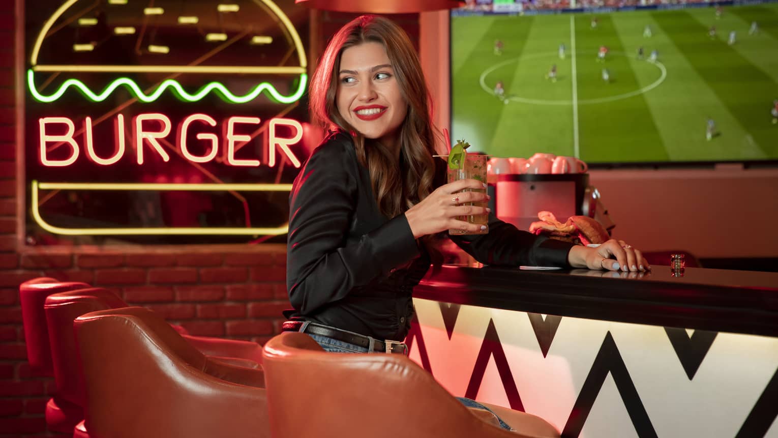 Smiling woman enjoys cocktail at the bar at Char Bar