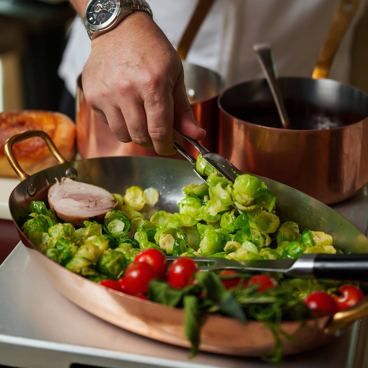 Chef's hands place Brussles sprouts into a large silver tray