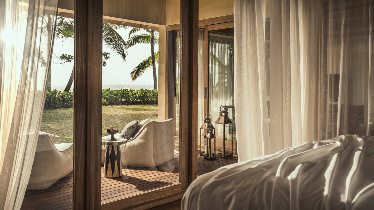Desroches Suite bedroom floor-to-ceiling glass patio doors, cushioned chairs on deck