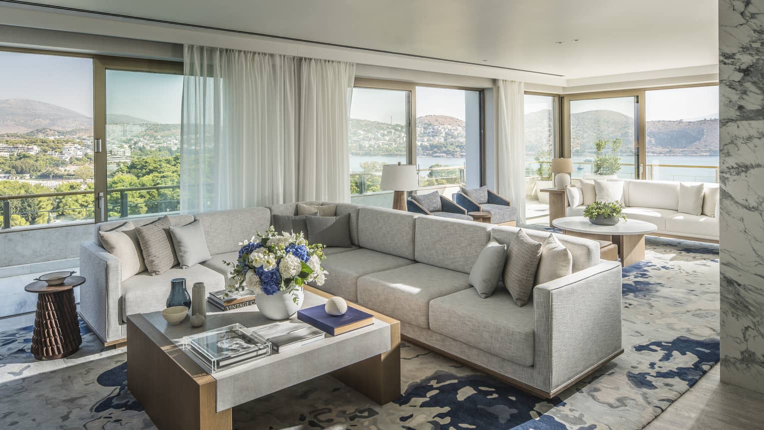 Arion Riviera Suite living area with white sectional sofa, square coffee table, patterned area rug, panoramic ocean views
