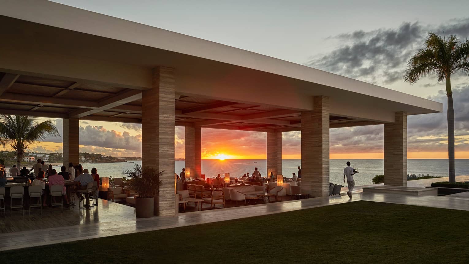 Sunset Lounge poolside bar and dining area at sunset, silhouette of palm tree