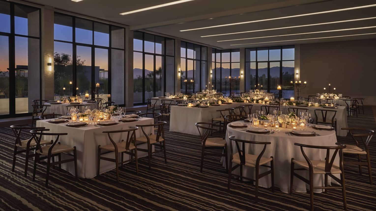 Ballroom with floor-to-ceiling windows and tables with candles.