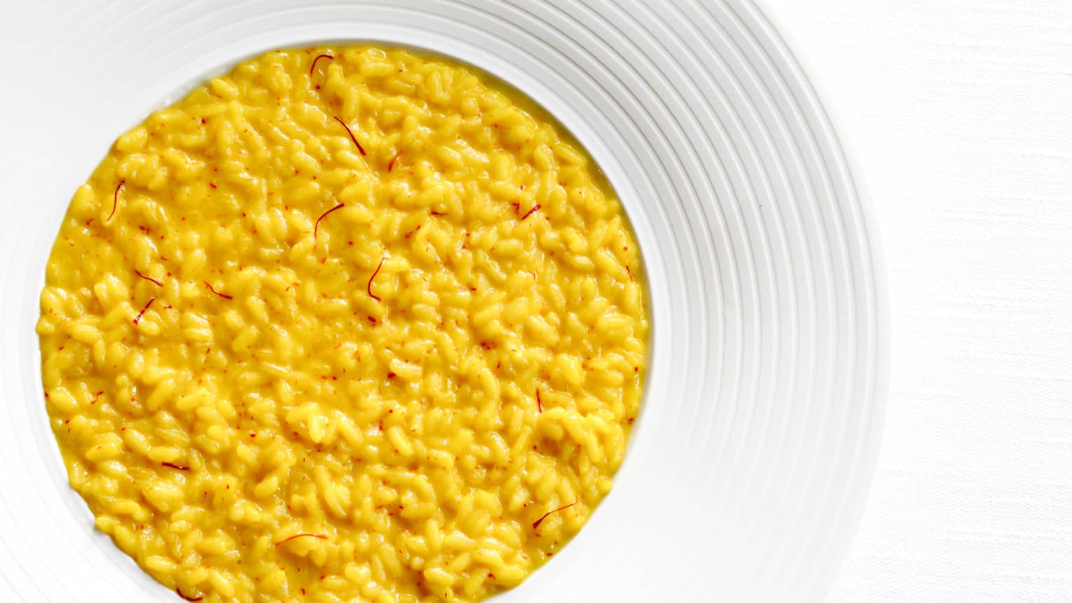 A yellow risotto dish garnished with fresh saffron