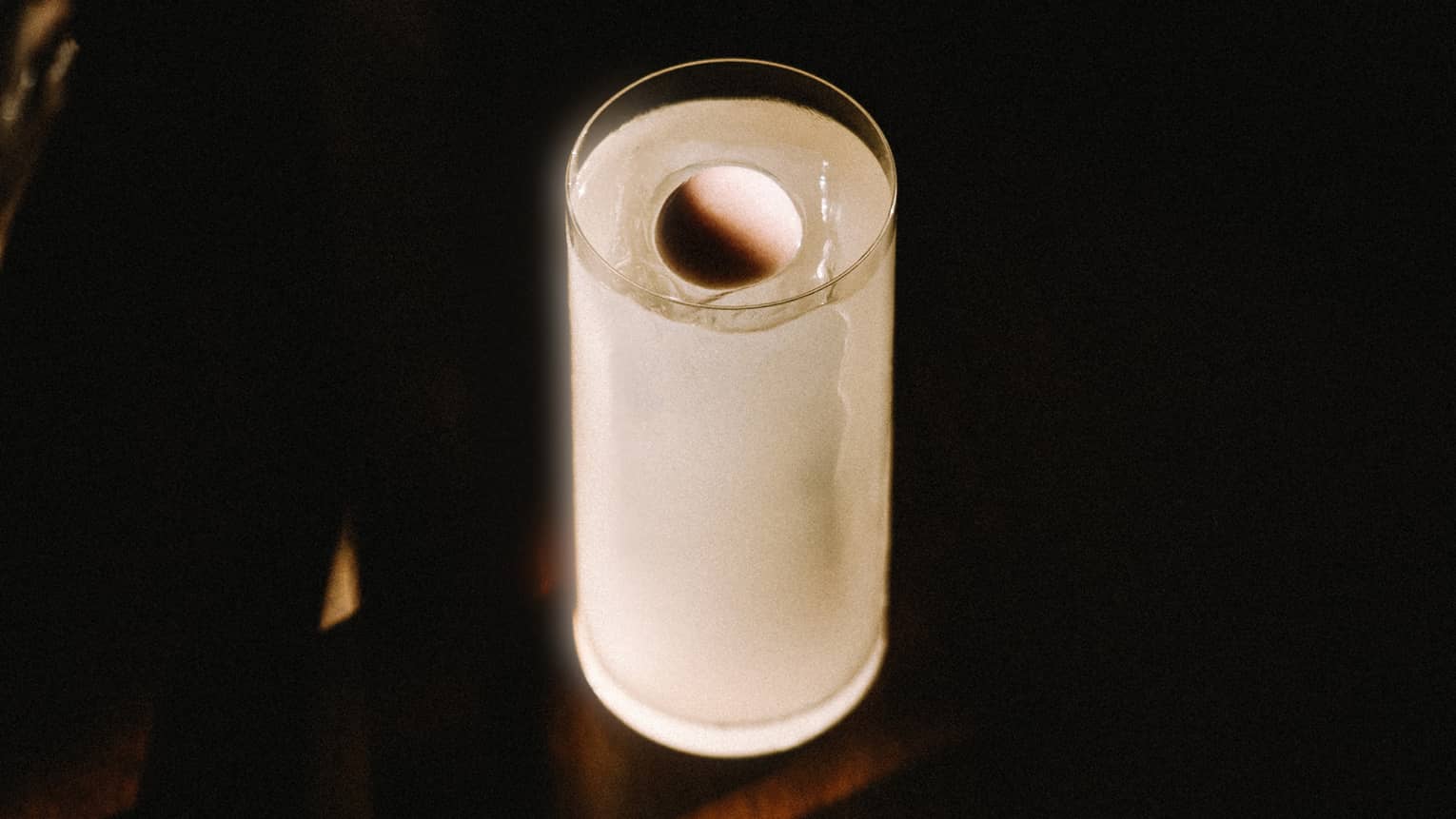 White-coloured cocktail served in a high ball glass