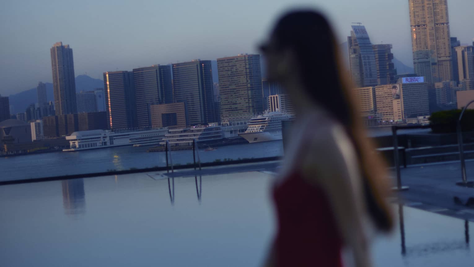 Woman walks along the edge of luxury hotel pool in city