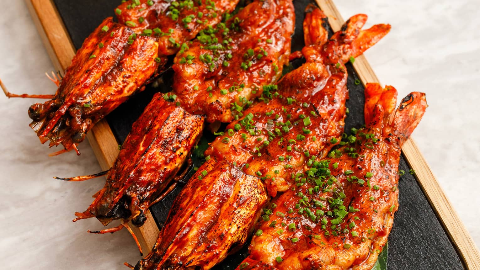 Char-grilled Prawns served on a wooden plank with sweet chili glaze and lemon zest