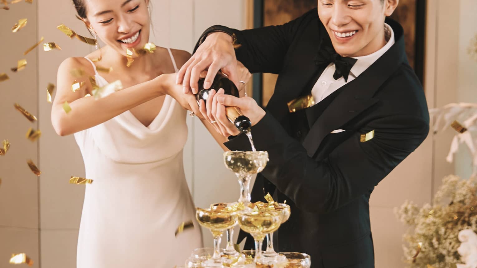 Bride and groom pour champagne into a champagne tower