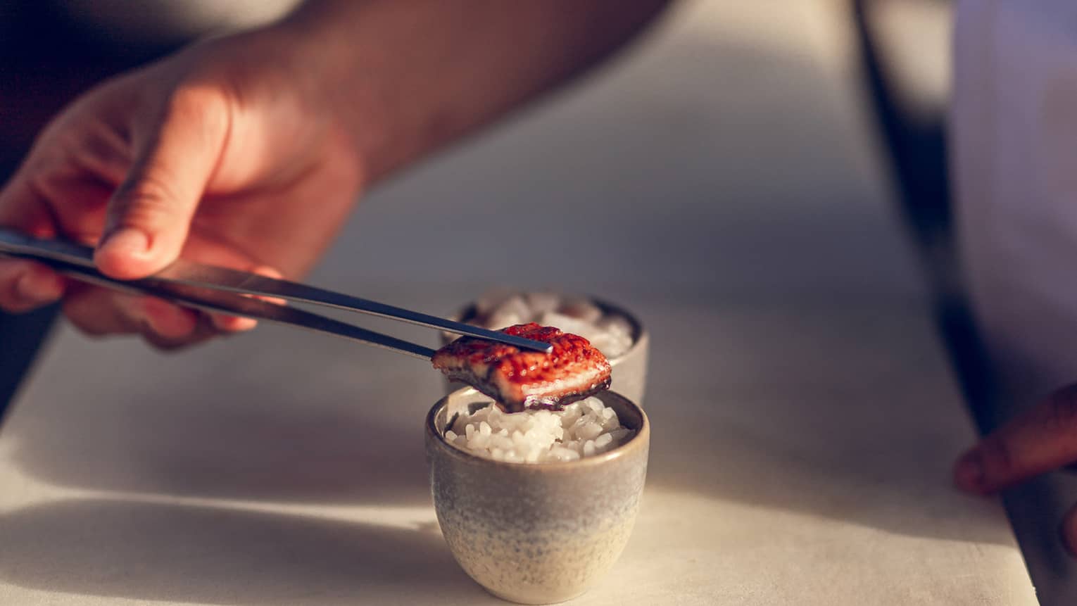Sushi cup, prepared by chef using chop sticks to plate