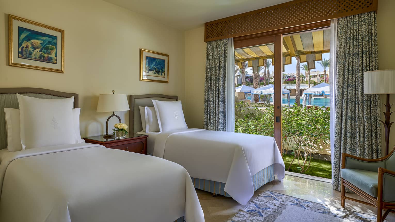 Bedroom with two twin beds, each with big Four Seasons pillow, and sliding glass doors to garden