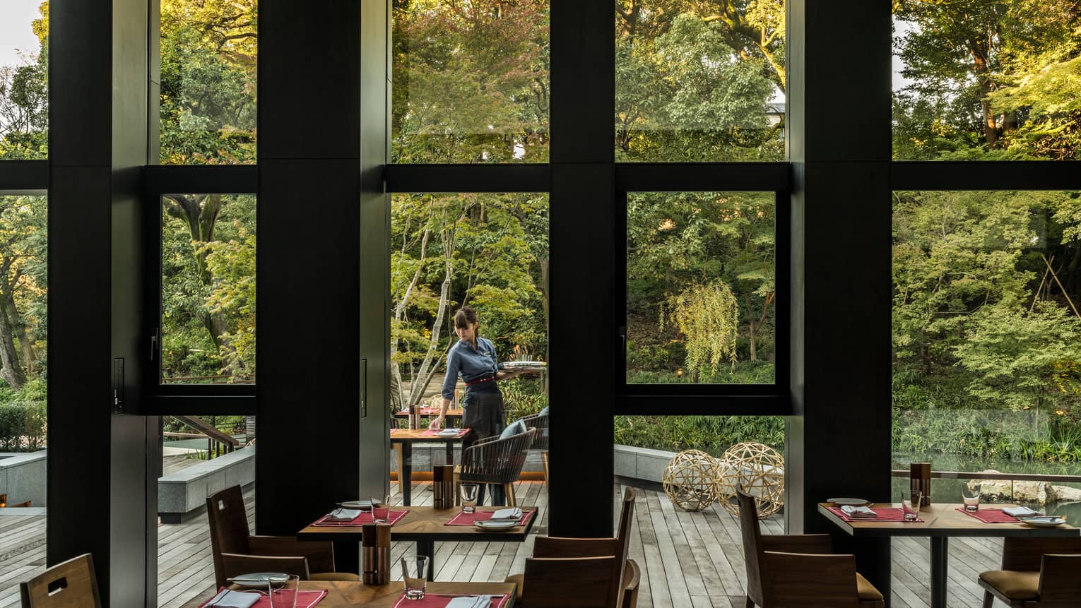 View of Brasserie patio and forest through window, server sets table