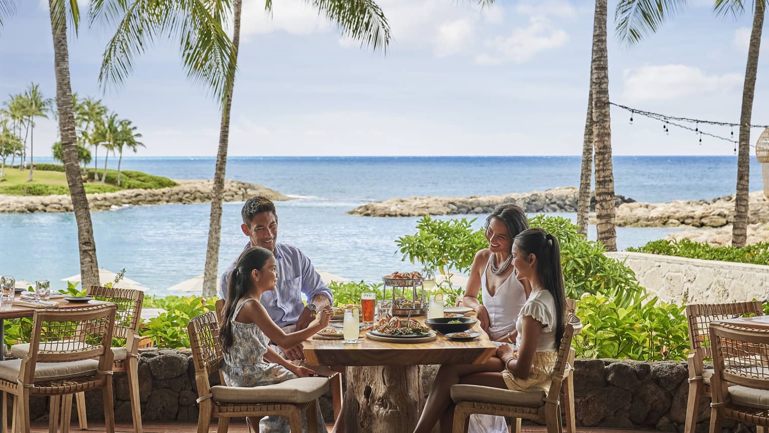 Family of four dining on Mina's Fish House beachfront patio