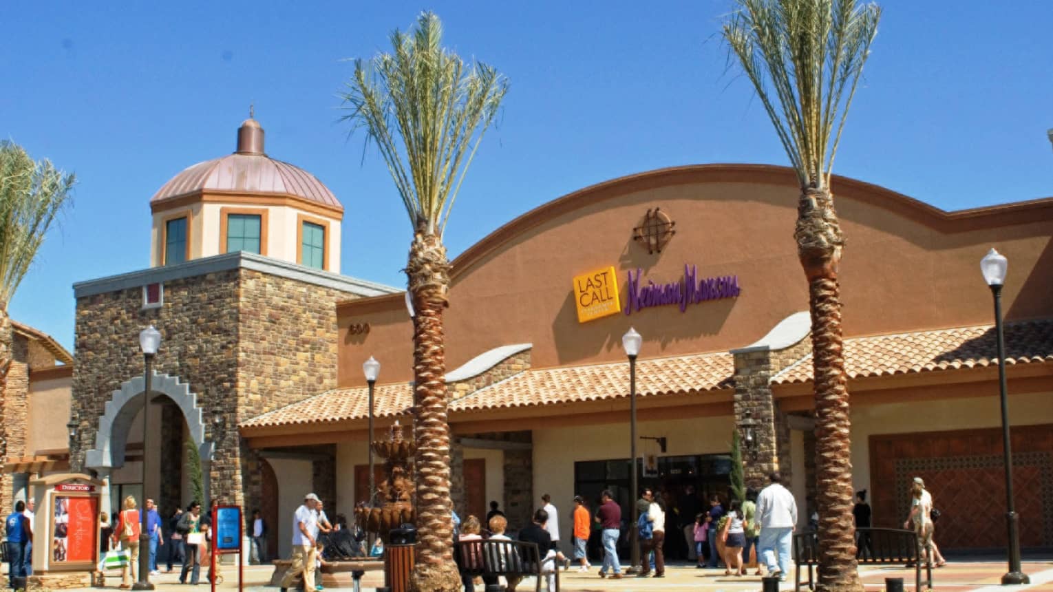 People wandering outside Westlake Village shopping mall with palm trees, blue sky 