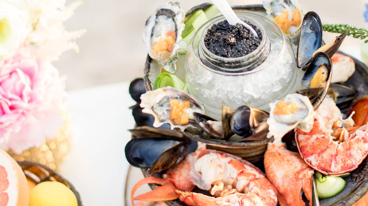 Seafood platter with fresh caviar, mussels, oysters and shrimp beside roses