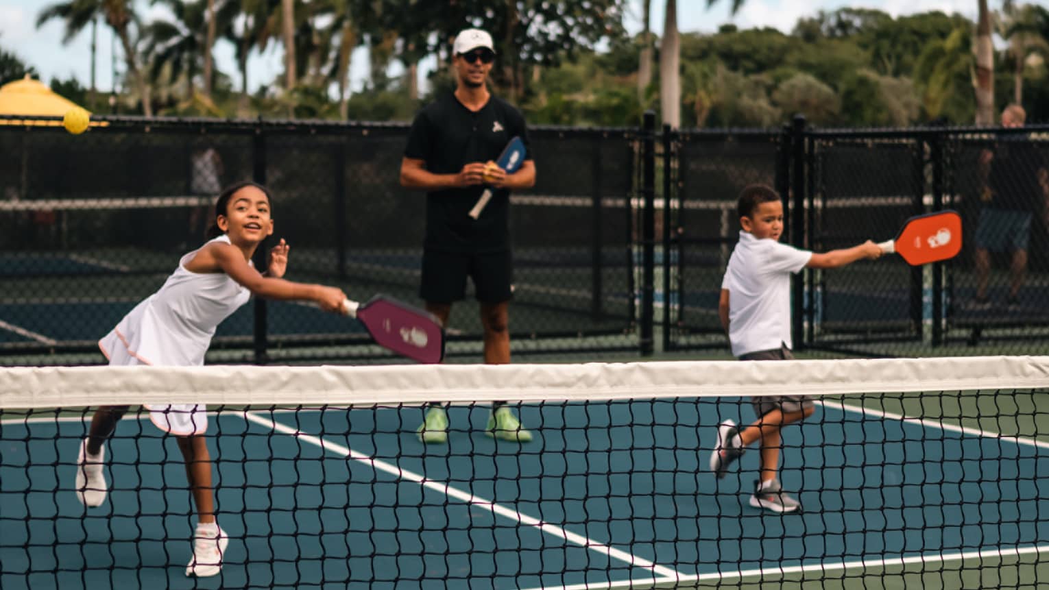 Two young children playing pickleball on a court.