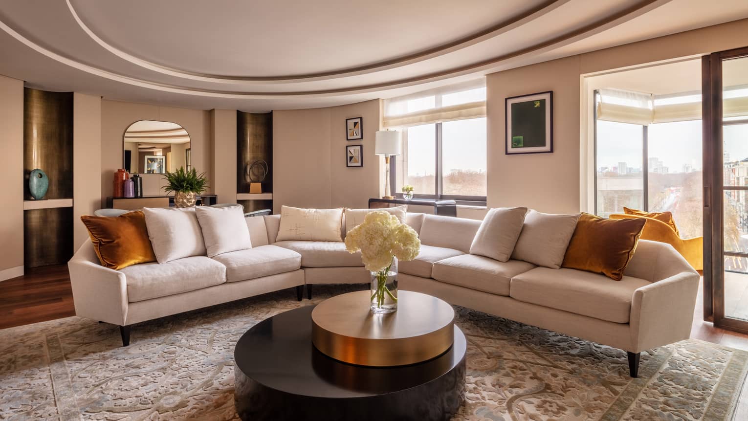 Hyde Park Lane Suite living room with beige sectional, round coffee table with white flowers in vase