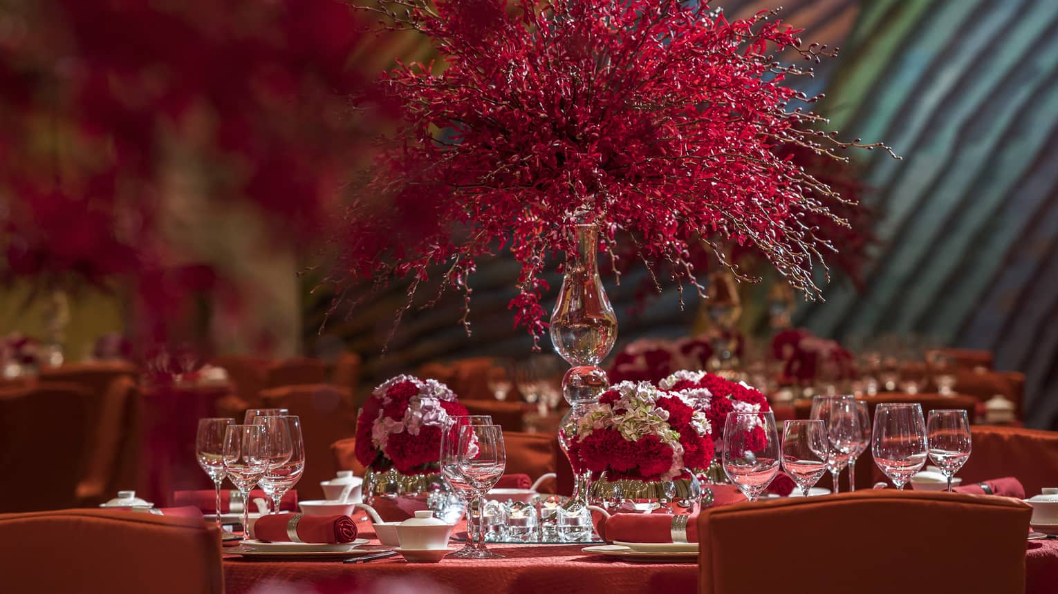 Close-up of banquet dining table with red tablecloth, red and white flower displays
