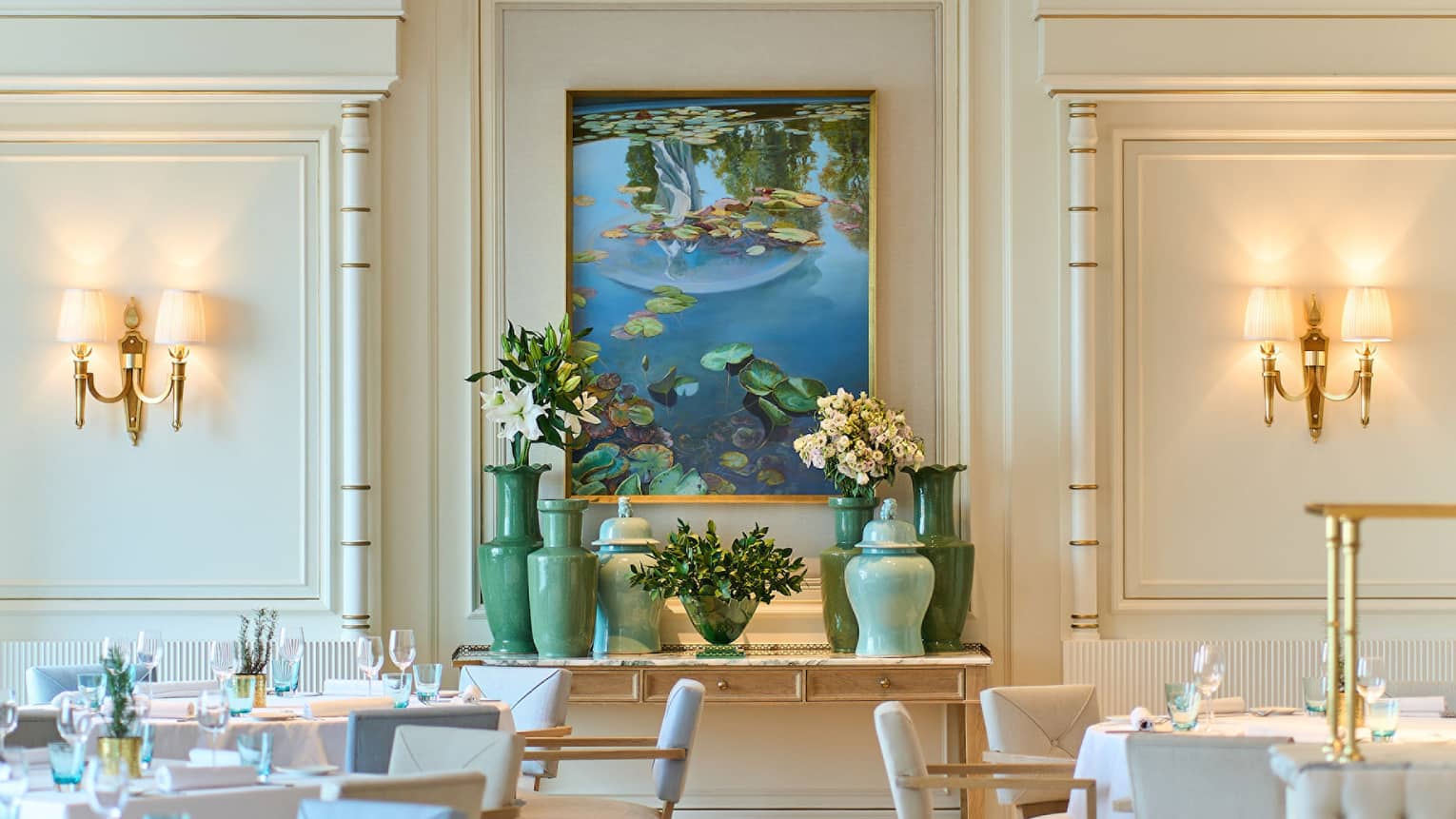 Brightly lit dining room of Riviera with lighted wall sconces, pale blue and white chairs, shiny patterned floor